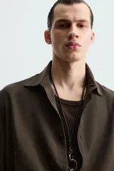 Camisa de corte relajado confeccionada en tejido con mezcla de modal, con cuello solapa, manga corta y cierre frontal de botones.