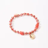 Pulsera elástica con cuentas facetadas color rojo y detalles dorados. Incluye un dije irregular dorado.