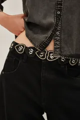 Cinturón elástico negro compuesto por una secuencia de piezas en forma de corazón. Cada corazón está decorado con bordados de mostacillas negras y apliques de cristales brillantes.