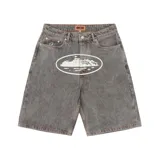 Short de jean gris con estampado blanco ovalado en el frente. Corte holgado y largo a la rodilla. Marca Corteiz, modelo Alcatraz.