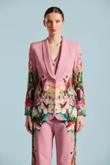 Saco de mujer Natalia Antolin con silueta estructurada, solapa chal y un llamativo estampado floral y botánico en tonos verdes, rojos y blancos sobre base rosada.