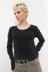 Remera negra de manga larga con cuello base y botones.