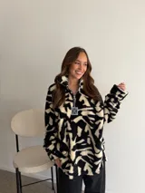 Buzo de peluche con estampado animal print de leopardo, cuello alto con cierre frontal parcial y tirador metálico decorativo.