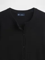 Saco de punto fino color marfil, con cuello redondo, cierre frontal con botones y mangas largas.