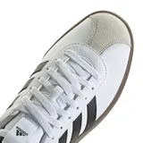 Championes urbanos Adidas modelo VL Court 3.0, con parte superior de cuero sintético blanco, icónicas tres tiras laterales en negro y puntera de gamuza gris. Presenta una suela de caucho vulcanizada en color marrón y cierre de cordones.