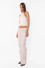 Pantalón cargo negro de corte recto y tiro bajo, con recortes y múltiples bolsillos laterales y traseros con tapa y botón a presión. Cierre frontal con cremallera de nylon y botón personalizado.