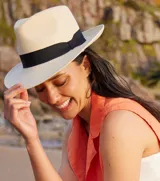 Sombrero tipo Panamá de paja color natural, con cinta negra alrededor de la copa.