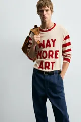 Camiseta de manga larga con cuello redondo, cuerpo color beige claro y mangas a rayas horizontales rojas y beige. Presenta texto frontal en relieve color rojo que dice "WAY MORE ART".