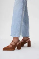 Zapatos de tacón tipo Mary Jane en gamuza color marrón, con doble tira con hebillas metálicas doradas sobre el empeine, punta cuadrada y taco bloque alto.