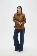 Camisa de algodón con estampado de manchas oscuras sobre fondo tostado, de corte holgado, manga larga, cuello clásico y cierre frontal con botones.