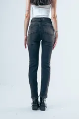Jean de corte skinny y tiro medio, confeccionado en denim elástico de color gris oscuro con efecto lavado. Presenta diseño clásico de cinco bolsillos, cierre frontal con botón y presillas en la cintura.
