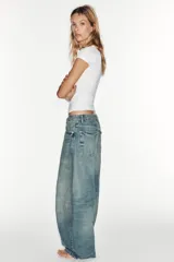Jeans de tiro medio y corte balloon color azul, con trabillas, bolsillos delanteros y traseros, y cierre frontal con cremallera y botón metálico.