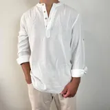 Camisa de lino color blanco con cuello mao y cierre frontal parcial con botones de madera. Presenta mangas largas con detalle de trabilla para arremangar.
