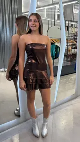 Vestido corto strapless de color marrón metalizado, con diseño de volados en la falda y acabado brillante.