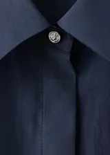 Camisa azul marino de lyocell y poliéster, con cuello camisero, manga larga, cierre frontal oculto con tapeta y detalles de apliques de strass y cristal en la parte delantera y las mangas.
