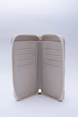 Billetera chica de cuero negro con textura tipo cocodrilo, cierre exterior, bolsillo para monedas con cierre en la parte trasera, múltiples ranuras para tarjetas y billetes, y forro rojo.