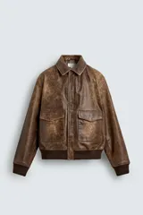 Cazadora relaxed fit de piel con acabado efecto vintage, cuello solapa, manga larga y cierre frontal con cremallera. Presenta bolsillos de plastrón con solapa en la cadera, bolsillo interior y acabados en rib elástico.