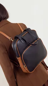 Mochila color bordó con doble asa superior, correas traseras regulables y bolsillo frontal con cierre. Se puede usar como mochila o como cartera.