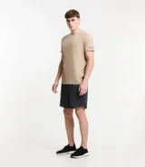 Remera deportiva de hombre con tecnología dry fit, cuello redondo y manga corta. Presenta un diseño liso en color beige con una pequeña etiqueta decorativa en el dobladillo.