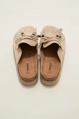 Suecos tipo mocasín color chocolate, confeccionados en material gamuzado. Presentan un diseño con flecos frontales, cordones decorativos con cuentas y una suela de plataforma plana de goma.
