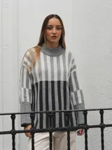 Sweater de punto con cuello alto, diseño a rayas verticales en tonos grises y blancos.