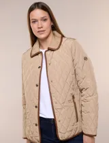 Campera matelaseada Michael Kors, de color beige con ribetes de ecocuero marrón. Cuenta con cuello con solapa, cierre frontal con broches metálicos, bolsillos laterales con cierre y mangas largas.