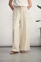 Pantalón de corte ancho y tiro alto, confeccionado en tejido de textura natural. Presenta cintura elástica con cordón ajustable, bolsillos laterales tipo parche y diseño de pierna recta y holgada.
