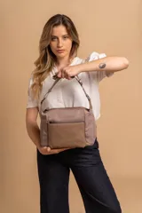 Bandolera de diseño práctico con combinación de texturas en tonos tierra, confeccionada en tela y símil cuero. Cuenta con un compartimento principal con cierre, un bolsillo frontal con cierre y correa ajustable para llevar al hombro o cruzada.