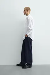 Camisa de corte slim fit confeccionada en tejido de algodón, con cuello italiano, manga larga con puños abotonados y cierre frontal de botones.