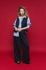 Camisa de algodón celeste con rayas verticales azul marino y marrón, cuello camisero clásico y cierre frontal de botones nacarados.