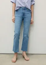 Jeans flare tiro medio color azul claro, con diseño crop y bajo deshilachado. Cuenta con presillas para cinturón, cierre frontal de cremallera y botón, y clásico diseño de cinco bolsillos.