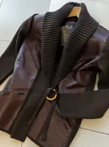Chaqueta de diseño combinado en color marrón, con paneles frontales de cuero y mangas y espalda de tejido de punto. Presenta un cuello solapa tejido, cierre frontal con hebilla metálica y bolsillos laterales.