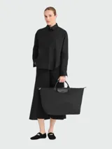 Bolso de viaje grande Longchamp modelo Le Pliage, color negro, confeccionado en nylon con detalles de cuero en las asas y solapa frontal con cierre de botón a presión.