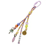 Llavero Rip Curl con tiras de cordón multicolor, mosquetón superior y múltiples dijes colgantes, incluyendo cuentas de colores, letras, una palmera y una tabla de surf.