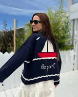 Cárdigan de tejido punto color azul marino, con diseño náutico bordado en la espalda que incluye un velero rojo y blanco, olas blancas y la inscripción "le port" en blanco.