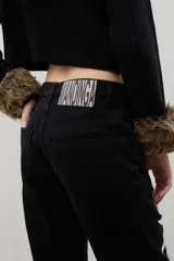 Pantalón de denim negro de corte recto con estampado floral blanco en ambas piernas. Cuenta con cierre frontal y bolsillos laterales.