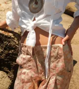 Shorts de brocato con estampado floral en tonos rosados y beige, con terminación de flecos en el ruedo.