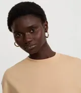 Remera cropped de manga corta, cuello redondo y calce oversized, confeccionada en tejido de algodón tipo media malla.