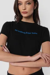Remera blanca de jersey corte baby tee con cuello alto de ribb complemento. Estampa en delantero con la frase "30 million dolar babe" en color azul.