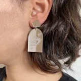 Aros colgantes con base superior negra y pieza inferior transparente con diseño de ojo grabado.