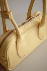 Cartera estilo baguette de cuero color marrón, con doble asa de hombro y cierre de cremallera. Hecha a mano en Uruguay.