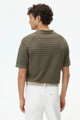 Polo de punto suave color verde militar con diseño a rayas horizontales oscuras, cuello camisero con escote en V y mangas cortas.