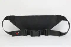 Riñonera de nylon color negro con estampado frontal del equipo Chicago Bulls en blanco. Presenta un cierre principal con detalle de cinta decorativa con logos de la NBA y tirador rojo.