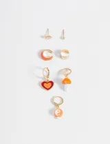 Set de aros dorados con dijes esmaltados de corazón, hongo y yin yang, además de dos aros tipo cuff y dos aros tipo pin con strass.