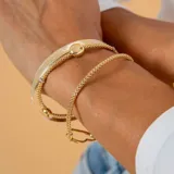 Pulsera de malla extensible en oro amarillo y blanco de 18k, con detalle de esfera central pulida.
