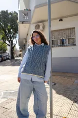 Chaleco tejido de punto con diseño de ochos, cuello redondo y sisa profunda. Presenta un detalle de terminación en color contrastante en el ruedo.