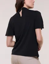 Blusa blanca de corte recto con cuello alto torzado, abertura frontal en gota y mangas cortas con aberturas sobre los hombros.