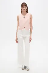 Musculosa cropped de viscosa color rosado, con cuello a la base, pequeña abertura frontal y detalle de hebilla metálica decorativa.