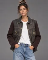 Campera Simona de cuero marrón oscuro con mangas tejidas de lana, cuello camisero, bolsillos frontales con solapa y hebillas metálicas, y cierre frontal con botones.