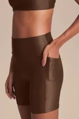 Biker deportiva de tiro alto confeccionada en tejido Allure con tecnología Lycra Adaptiv, de compresión media a alta, con acabado satinado y bolsillos laterales funcionales.